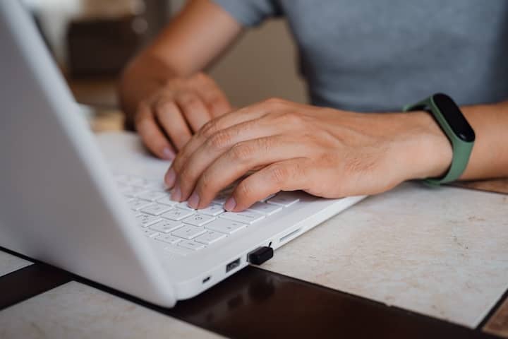 Hands typing on a laptop